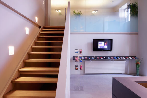 Pan event Ticketbüro | Paul Szimak Stilvolle Treppe mit einem TV darüber, der das moderne Design des Raumes unterstreicht.